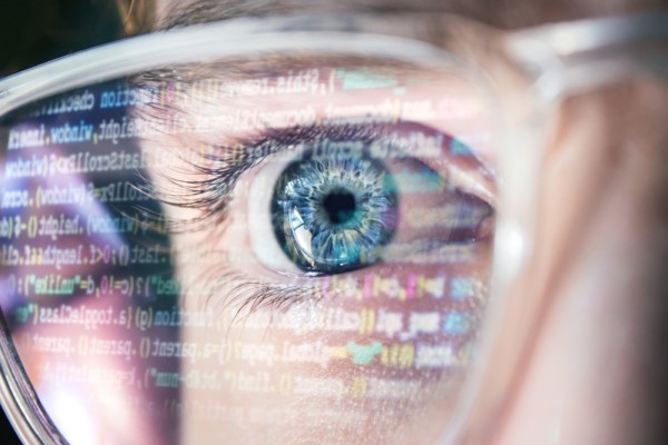 Computer code reflected in glasses on man, AI